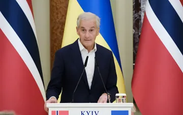 Прем'єр-міністр Норвегії виступає біля трибуни з написом KYIV на тлі прапорів України та Норвегії, анонсувши допомогу на 85 млрд крон