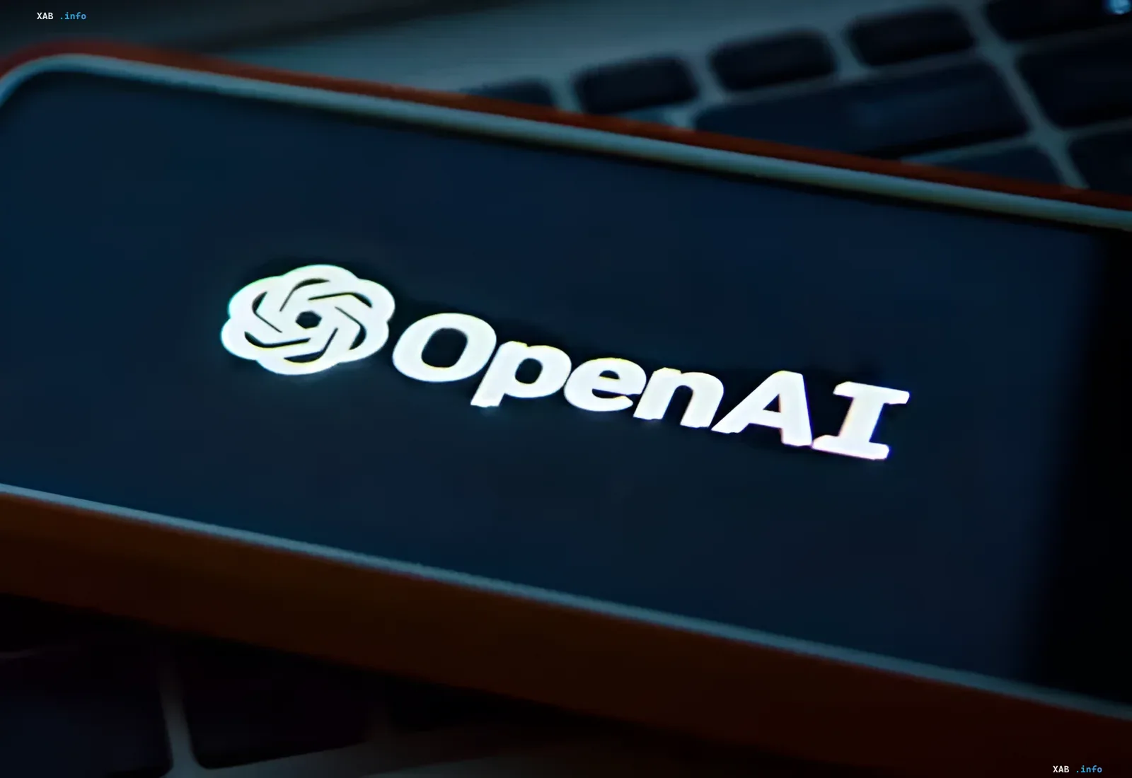 OpenAI-Logo auf dem Smartphone-Display, das auf einer Laptop-Tastatur liegt