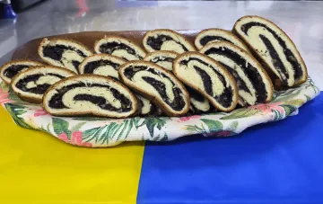 Украинские полярники на станции в Антарктике нарезали праздничный «Пирог Независимости» с тёмной начинкой к 24 августа; жёлто-синий фон стола отсылает к флагу Украины