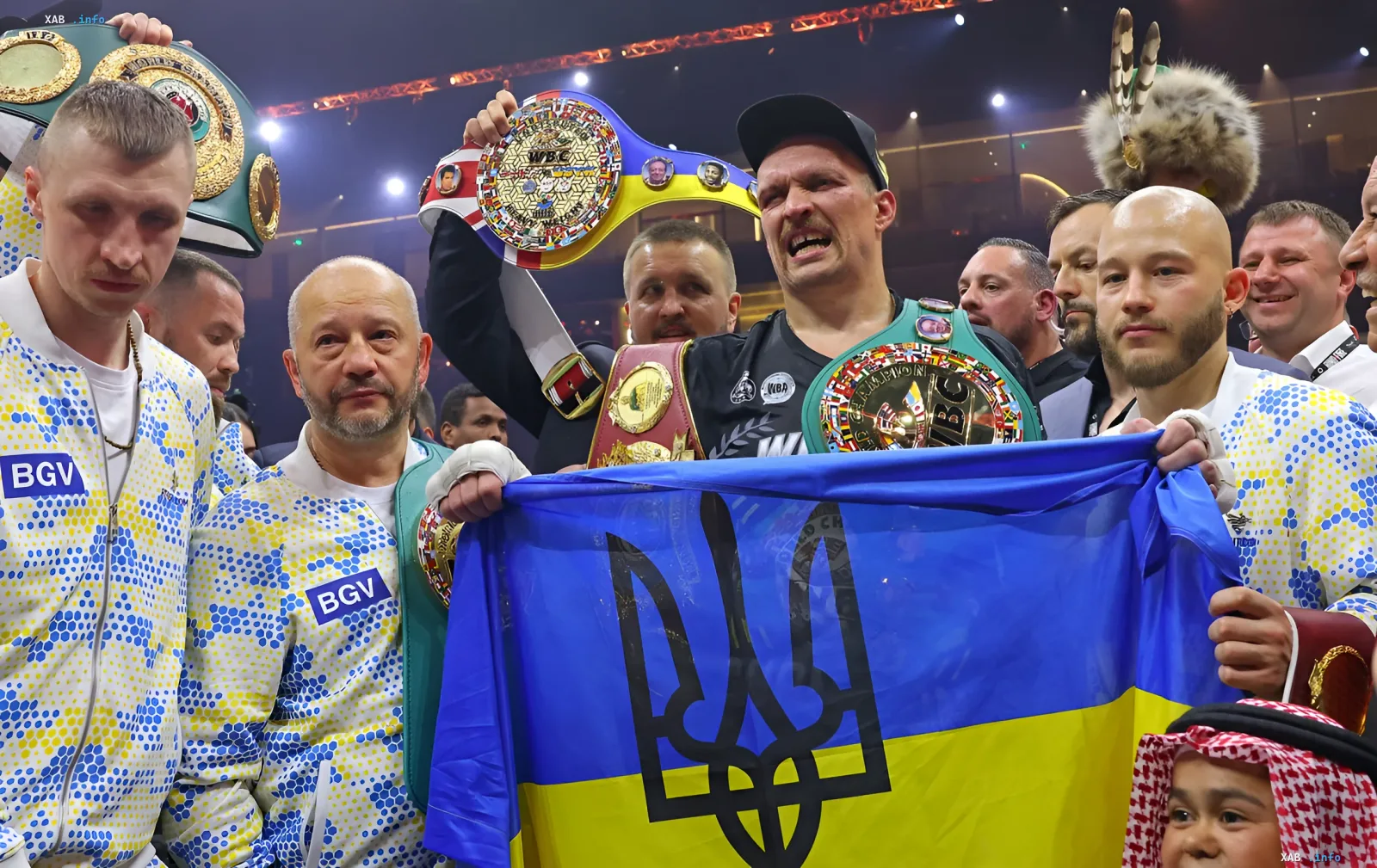 Боксёр с чемпионскими поясами WBC и WBA на фоне флага Украины с тризубом