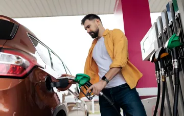 Водій заправляє автомобіль на АЗС у день, коли ціни на паливо стабілізувалися, але розкид між мережами сягає 5 гривень за літр