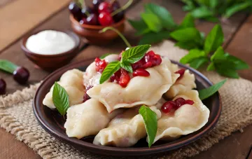 : Kirschen-Varenyky (Teigtaschen) mit Sauerrahm und frischen Kirschen — ein traditionelles ukrainisches Gericht zum Unabhängigkeitstag