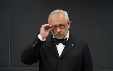Заместитель генерального директора РБК-Украина в очках и бабочке на фоне темного интерьера