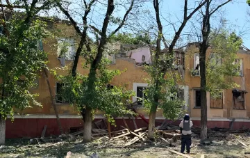 Beschädigtes Mehrfamilienhaus in Kramatorsk nach einem Luftangriff: zerstörtes Dach, Trümmer und ein Soldat im Vordergrund