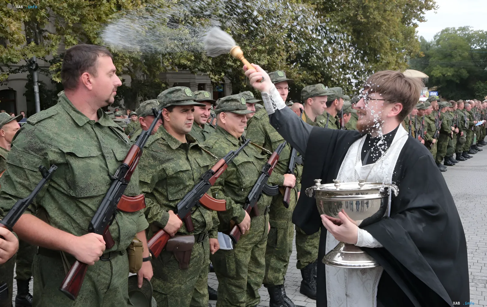 Priester segnet mobilisierte russische Soldaten mit Gewehren mit Weihwasser bei einer Parade