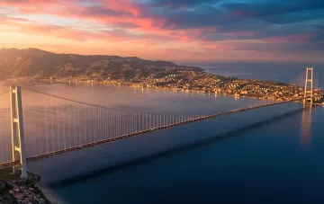 Hängebrücke über die Straße von Messina bei Sonnenuntergang, die Sizilien mit dem italienischen Festland verbindet