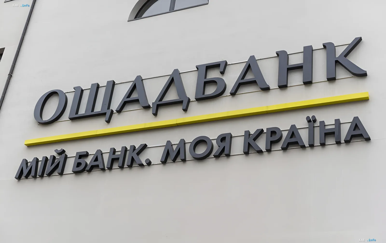 Вывеска Ощадбанка на фасаде здания на фоне новости о сбое сайта и мобильного приложения