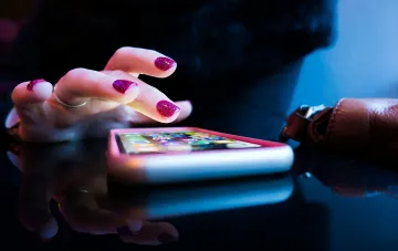 Frauenhand über einem Smartphone auf glänzender Oberfläche: Wahl zwischen Samsung Galaxy und Google Pixel