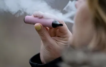 Person raucht eine rosa E-Zigarette mit dichtem Dampf im Hintergrund — Illustration zum Kantar-Report, wonach 93,3 % der E-Zigaretten in der Ukraine dem Gesetz nicht entsprechen