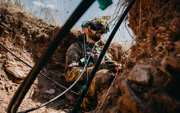 Военнослужащий Сил обороны в цифровом камуфляже с VR-шлемом в окопе во время симуляционного обучения для ударов по объектам в тылу РФ