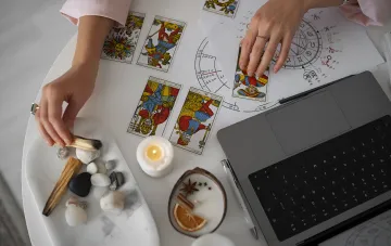 Tarot card spread and natal chart with zodiac symbols on an astrologer's desk for the August 25 2026 horoscope