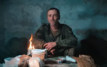 Russian soldier captured by Ukrainian forces on the Zaporizhzhia front sits in a dilapidated room by a flame