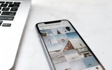 Smartphone mit offenem Instagram-Profil neben einem Laptop: Illustration der First-Draft-Funktion, die Reels aus deinem Inhalt in 10 Sekunden automatisch zusammenstellt
