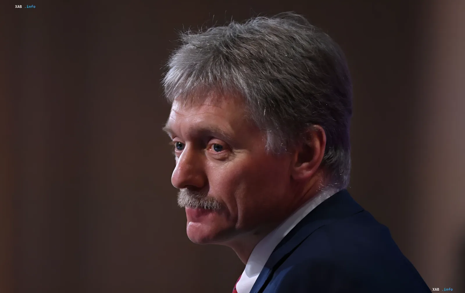 Kreml-Sprecher Dmitri Peskow in dunklem Anzug vor gedämpftem braunem Hintergrund beim Kommentar zum Moskau-Besuch des CIA-Direktors Ratcliffe