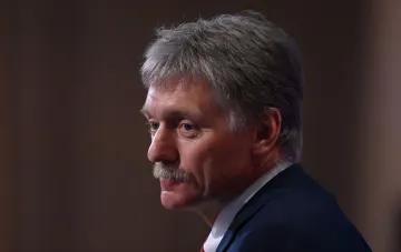 Kreml-Sprecher Dmitri Peskow in dunklem Anzug vor gedämpftem braunem Hintergrund beim Kommentar zum Moskau-Besuch des CIA-Direktors Ratcliffe