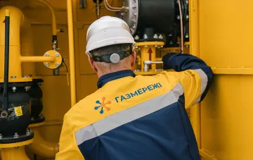 Работник аварийной бригады «Газмережі» в каске и защитных очках обслуживает газовое оборудование на объекте газотранспортной инфраструктуры