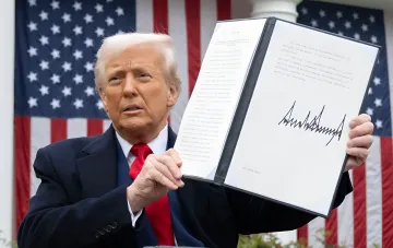 Дональд Трамп держит подписанный документ о 30-летней ядерной сделке с Саудовской Аравией на фоне флагов США перед передачей Конгрессу