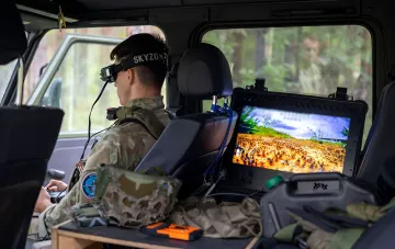 Оператор в камуфляже с VR-очками SKYZONE и монитором симуляции дроновой атаки на учениях JATEC и НАТО в Латвии