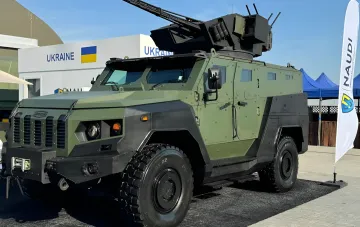Украинский бронированный автомобиль с зенитной установкой на стенде ОПК на международной выставке, демонстрирующий потенциал отрасли для иностранных инвестиций