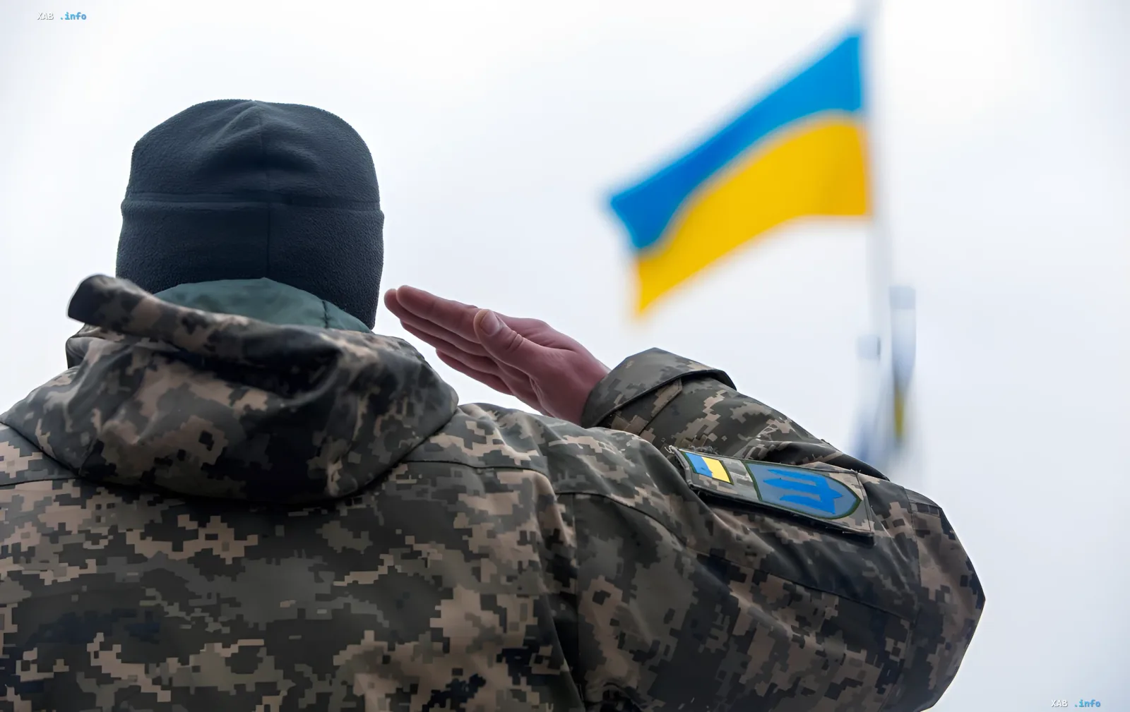 Украинский военный в камуфляже отдает салют украинскому флагу на фоне новости об упрощенном возврате из СЗЧ