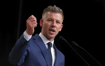 Politician at a podium with microphones during a speech on European security and Hungary's stance on the threat from Russia