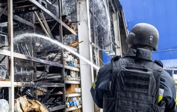 Рятувальник у захисному шлемі оглядає наслідки денної атаки дронів та артилерії по цивільних об'єктах в Україні
