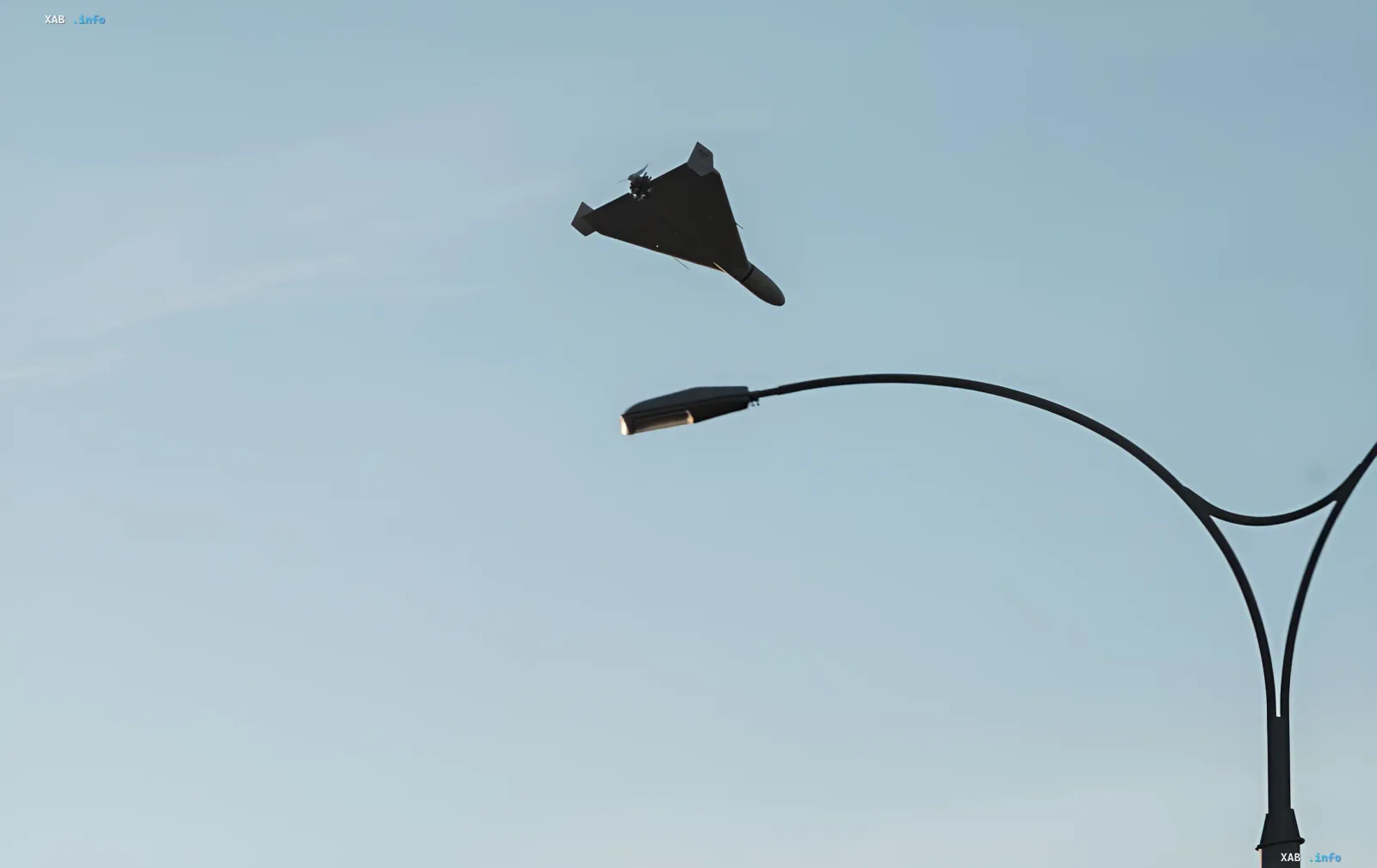 A jet-powered drone flies over Kyiv against a clear sky near a street lamp during the August 27 drone attack