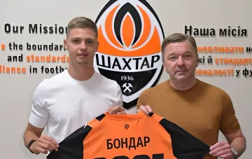 Valeriy Bondar and a Shakhtar representative holding the club jersey in front of the Shakhtar logo
