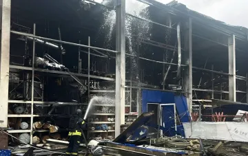 Ліквідація осередків горіння після удару дрона по гіпермаркету «Епіцентр» в Харкові: пожежник гасить зруйновану будівлю