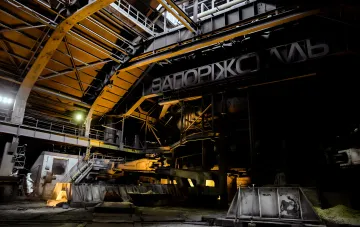 Walzwerk des Stahlwerks Saporischtschalsch mit dem Werksnamen am Gebäude nach dem nächtlichen Angriff: stillgelegte Produktion und dunkle Hallen des Komplexes