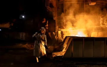 Arbeitnehmer der Swerdlow-Stahlwerke (Saporischschja) in Schutzbekleidung neben einem Ofen mit flüssigem Metall vor der Bedrohung durch Raketenangriffe auf die ukrainische Metallurgie
