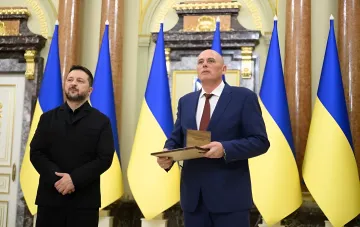 Президент Зеленский вручает награду «Национальная легенда Украины» директору Приднепровской ТЭС ДТЭК на фоне украинских флагов