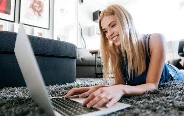 Lächelnde Frau mit Laptop: Zwillinge führen das Ranking der Sternzeichen an, die am meisten lügen