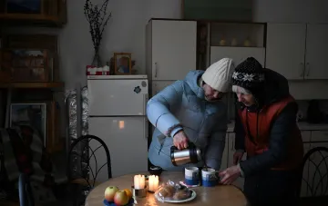 Жінки в зимньому одязі п'ють чай у домі в Херсоні, переживаючи зиму в безпечному регіоні