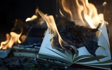 Brennendes Buch vor Flammenhintergrund: Folgen des Nachtangriffs auf das Lager des Verlags A-ba-ba-ga-la-ma-ga