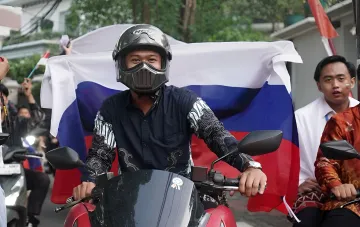 Молодий індонезієць у шлемі на мотоциклі з національним прапором Індонезії — ілюстрація до сюжету про вербування громадян Індонезії для бойових дій