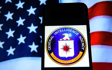Emblem der US-Zentralnachrichtendienstes (CIA) auf einem Smartphone-Bildschirm vor dem Hintergrund der US-Flagge — Symbol für den geheimen Besuch von CIA-Direktor Ratcliffe in Moskau