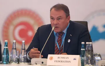 Представитель РФ за столом переговоров с табличкой Russian Federation на фоне логотипа форума — контекст заявлений о бомбардировках украинских городов