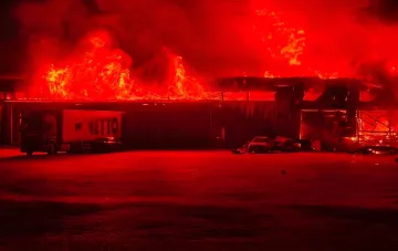 Fire at a logistics warehouse in Kyiv region after a strike: flames over the roof and a NETTO truck in the foreground