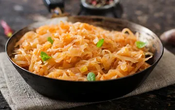 Geschmortes Kohl nach ukrainischem Rezept in einer Gusseisen-Schüssel, garniert mit frischem Kraut — der Schlüssel zu einem perfekten Gericht ohne Bitterkeit