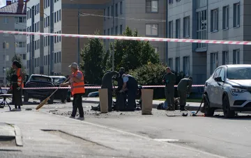 Ort der Autodetonation in Sankt Petersburg: Rettungskräfte in orangefarbenen Westen und Soldaten räumen Trümmer hinter dem Absperrband