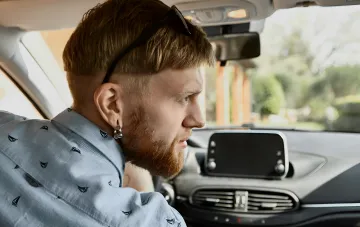 Fahrer im Auto mit eingeschalteter Klimaanlage, die unangenehme Gerüche abgeben kann