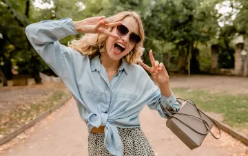 Frohe Löwen-Frau im Park macht 'ok'- und 'Sieg'-Gesten, zeigt Liebe zu Aufmerksamkeit und Komplimenten