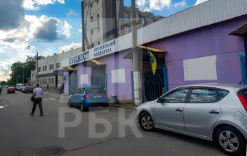 Фасад торгового книжного рынка «Букинист» на Почайне в Киеве с вывеской и припаркованными автомобилями после восстановления