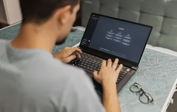 Человек работает на ноутбуке с открытым интерфейсом ChatGPT на фоне новости о том, что Claude обогнал ChatGPT в рейтинге удовлетворённости YouGov
