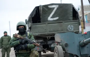 Військовий з автоматом на тлі вантажівки з літерою Z та бронетехніки в контексті розвідувальних оцінок щодо підготовки Росії до можливого конфлікту з НАТО