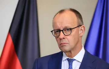 Friedrich Merz im blauen Anzug vor der deutschen Flagge: Kanzler bereitet breite Sanktionen gegen Russland nach dem Drohnenvorfall in Leipzig vor