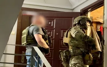 Сотрудники правоохранительных органов в тактическом снаряжении задерживают подозреваемого на лестнице в Одессе
