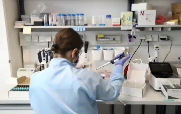 Исследователь в защитной экипировке работает с пипеткой в лаборатории по изучению опасных патогенов на острове Лысый