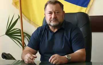 Тарас Дидич, глава Дмитриевской общины на Киевщине, погибший при российской атаке, за рабочим столом на фоне украинского флага